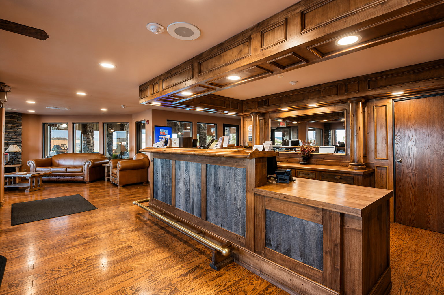 Front desk and lobby seating at Pinedale Hotel & Suites — wood-paneled reception, leather seating, hardwood floors